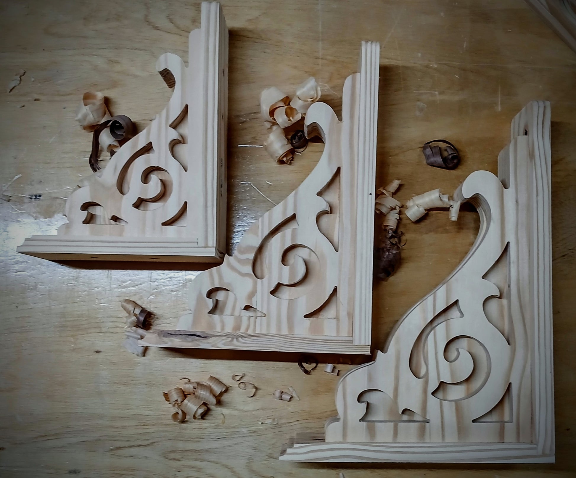 Wooden decorative brackets with intricate carvings on a wooden surface.