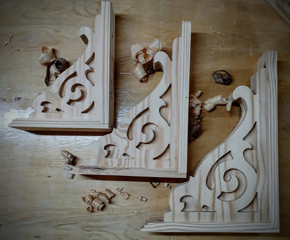 Wooden decorative brackets with intricate carvings on a wooden surface.